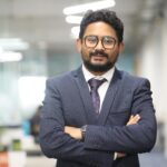 Confident man in a suit standing in a modern office, showcasing professionalism.