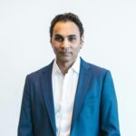 Portrait of a confident businessman holding papers in formal attire inside an office
